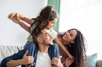 mom and dad playing with daughter on a couch